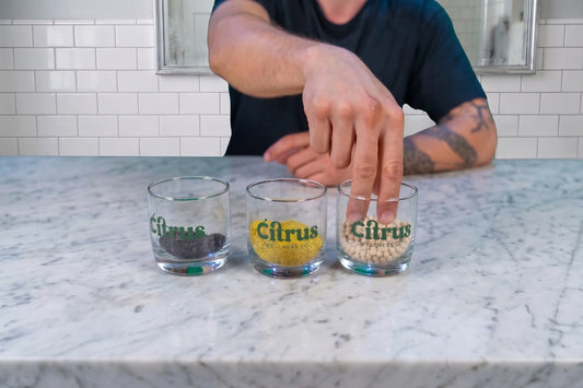 Three cups containing filtration media: KDF-55, granular activated carbon, and Vitamin C ceramic balls