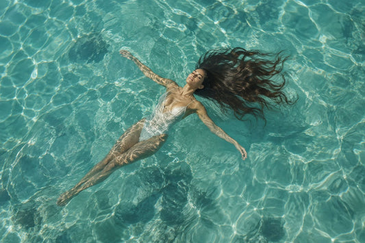 Woman with long flowing hair floating in crystal clear water