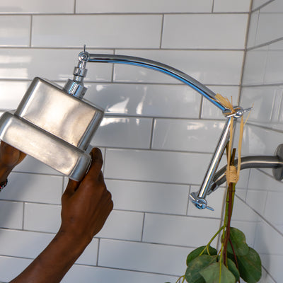 A person adjusting a showerhead attached to a shower arm extender