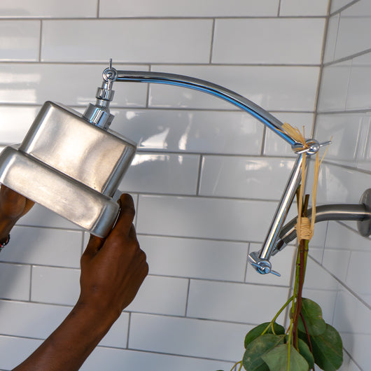A person adjusting a showerhead attached to a shower arm extender